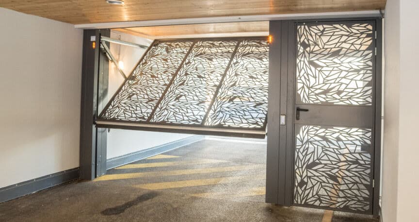 Porte de garage basculante à tôle découpée posée par ACOMA en pied d'immeuble