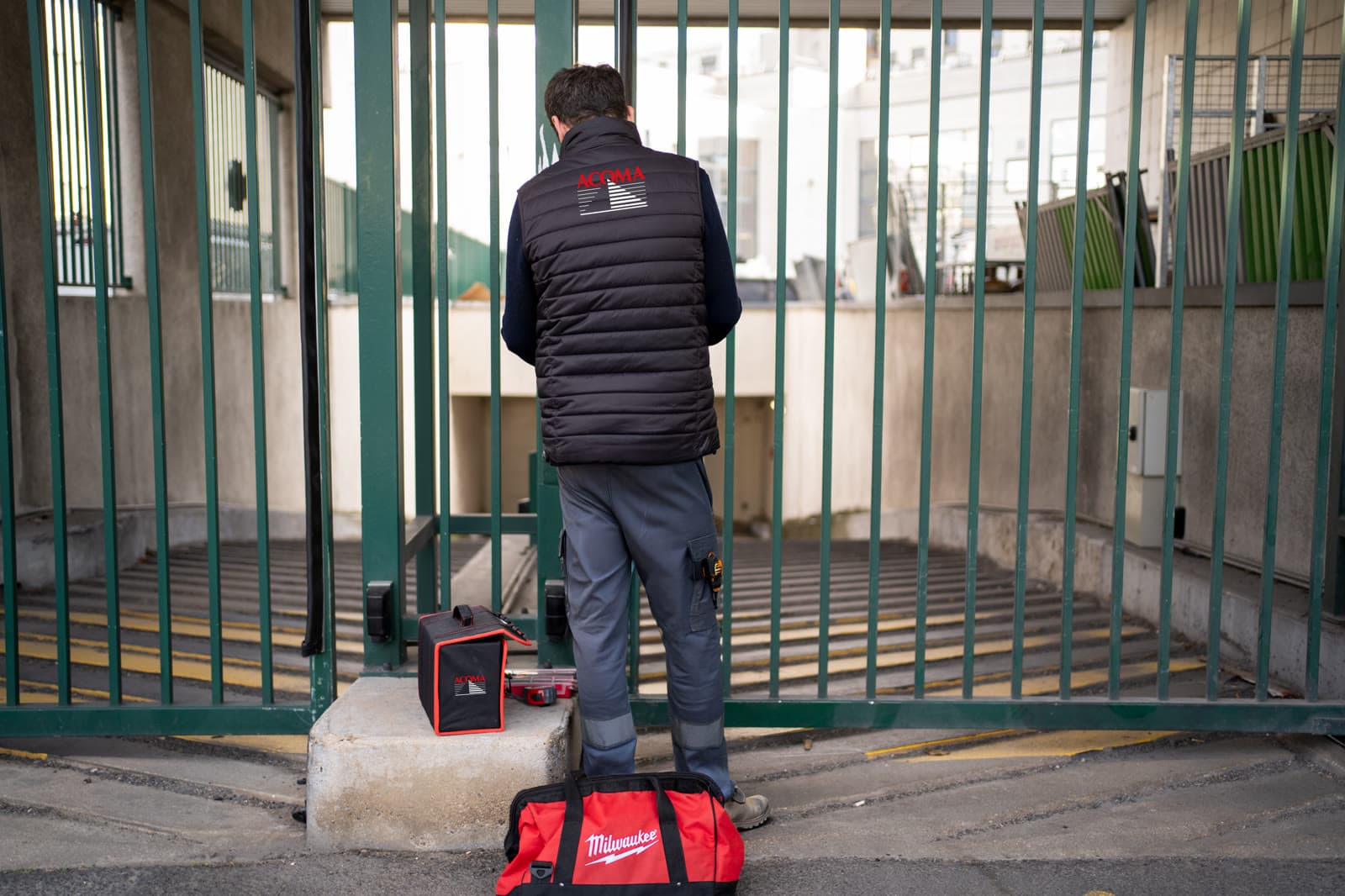 Technicien ACOMA sur un portail coulissant motorisé à l'entrée d'un parking